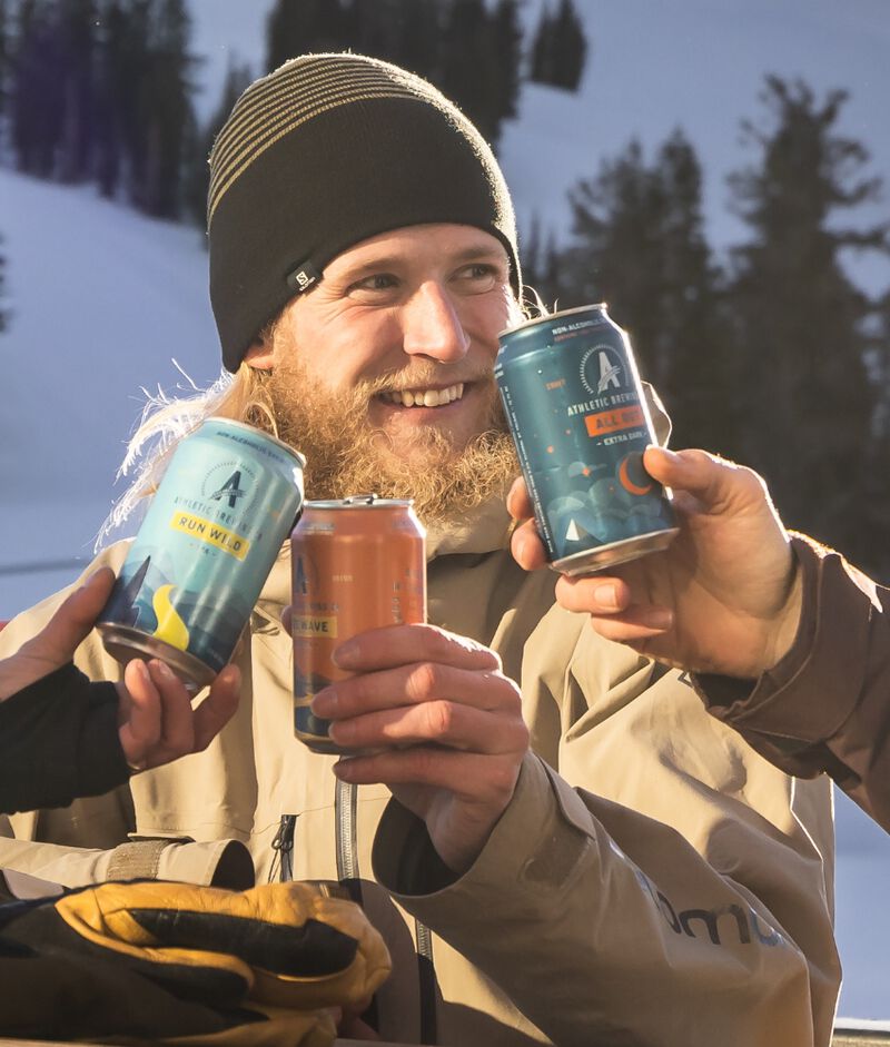 Friends enjoying Athletic Brewing Company beer on a snowy mountain