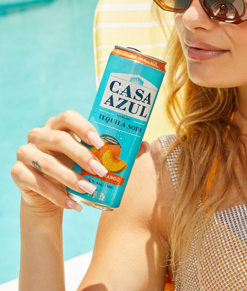 Woman holding a can of Casa Azul Tequila Soda Peach Mango